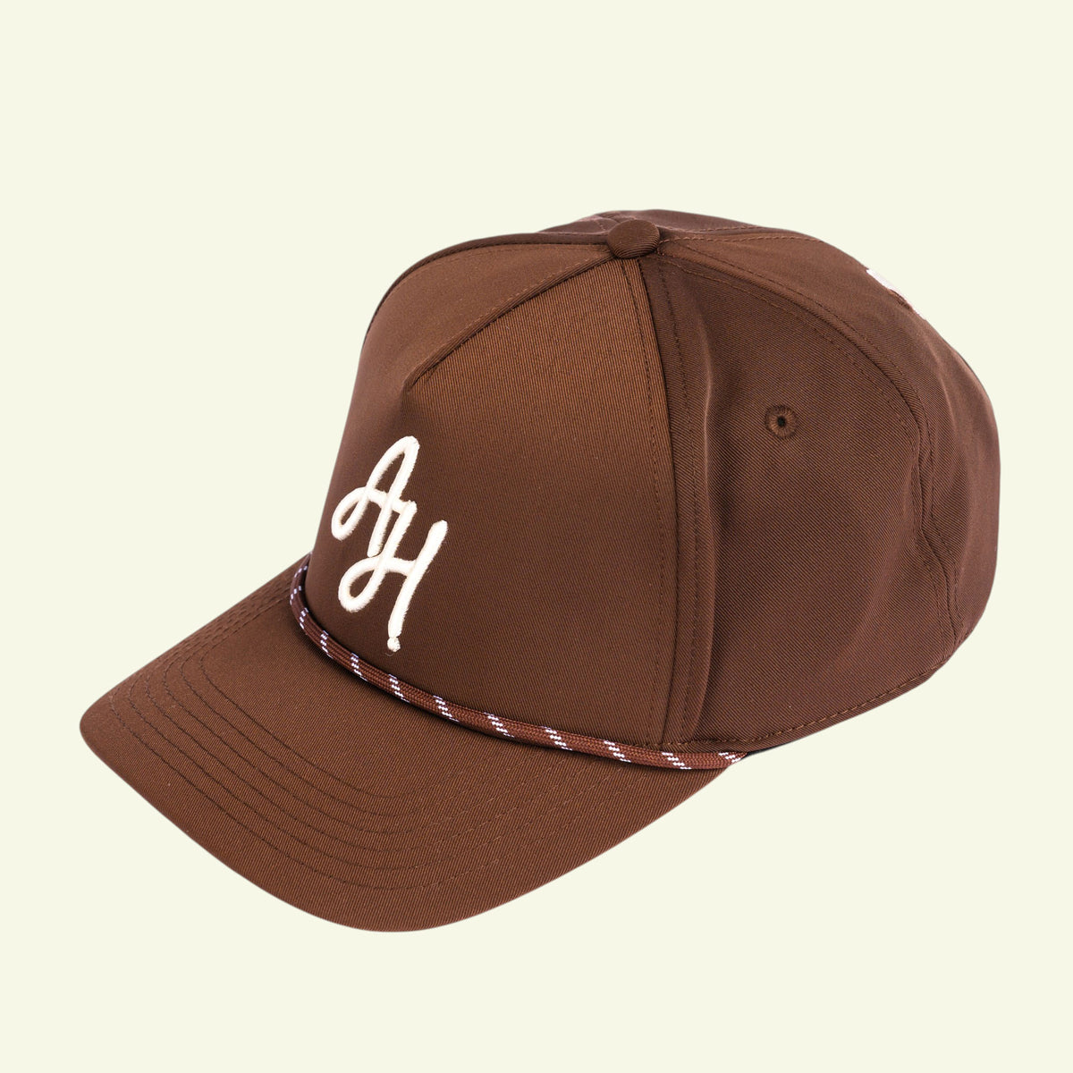 Close-up of white AH embroidery and brown and white braided rope on a brown golf cap