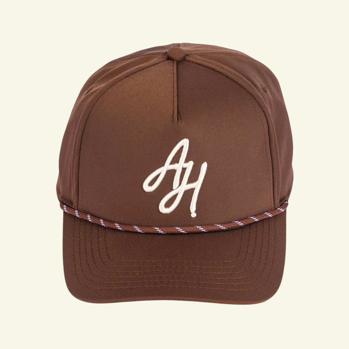 Brown A-frame rope cap, three-quarter view with white AH monogram and braided rope across the brim